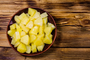 Ceramic plate with chopped canned pineapple on wooden table. Top view