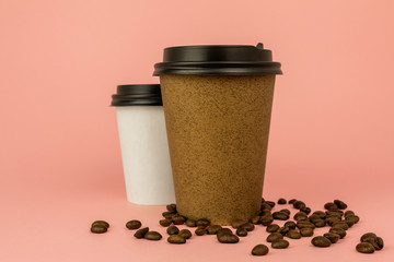 Two coffee cups and coffee beans on colored pink background. Coffee to go containers.
