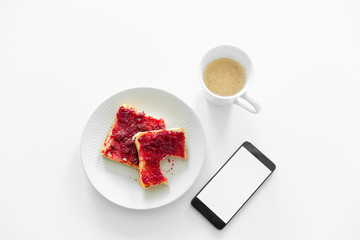 Breakfast is on the table. A cup of coffee and toast with cherry jam next to the phone