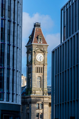 Fototapeta na wymiar Old clock tower between new glass buildings