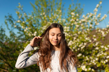 Naklejka premium Portrait of a young beautiful teenager girl in a blooming spring green garden