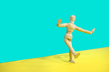 Fototapeta na wymiar Wooden mannequin posing over yellow and green background