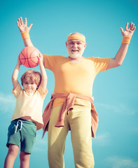 Grandfather and child training together. Be in motion. Senior man and child in family health club. Senior man and child exercising on blue sky.