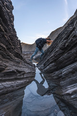 Deba, Gipuzkoa / Spain »; January 26, 2020: A young woman exploring the Sakoneta coast geopark among stones one morning