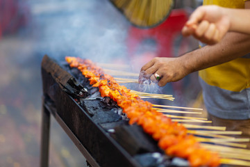 Street food seller in Asia fries chicken mini barbecue on the grill