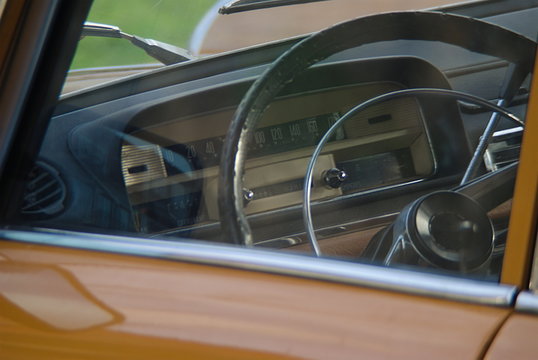 Vista para o interior de um carro antigo, volante e tablier
