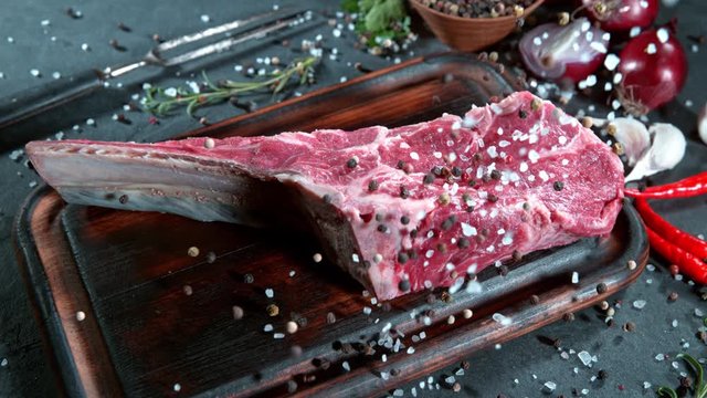 Super Slow Motion Shot of Falling Fresh Tomahawk Meat and Seasoning on Cutting Board at 1000 fps.