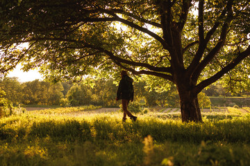 Active male traveler walking in green forest in sunny day