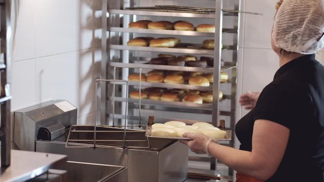 The woman chef is turning the donut bases on another side before frying.