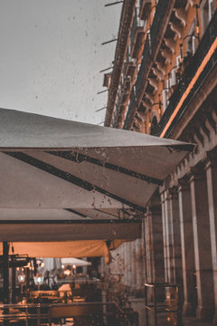 toldo blanco resistiendo fuerte lluvia en plaza mayor con fondo anaranjado