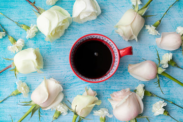 Cup of coffee surrounded by white roses