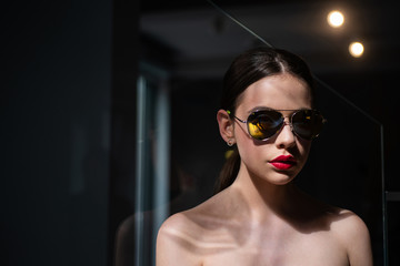 Beautiful young model with big glasses-close up. Beautiful fashion model posing with glasses. Close-up portrait of a beautiful charming young attractive lady. Fashionable youth style. Female fasion.