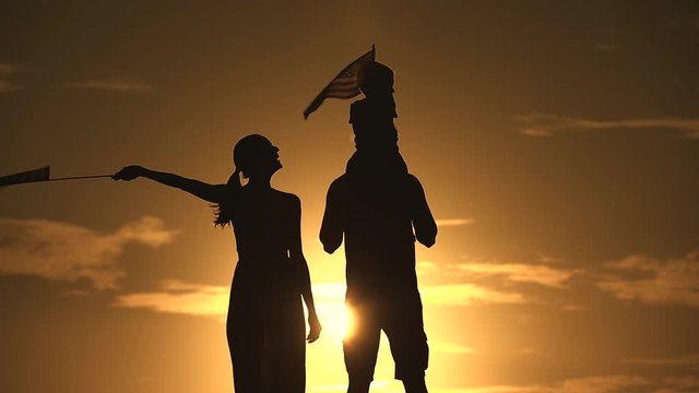 Patriotic silhouette of family waving American USA flags. 