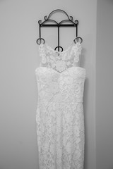 The wedding dress is hanging on a hanger in the room.