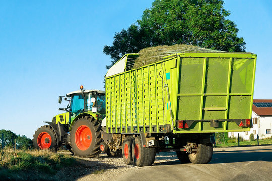 Tractor with trailer full of hay on the road in Bourgogne-Franche-Comte region, France.