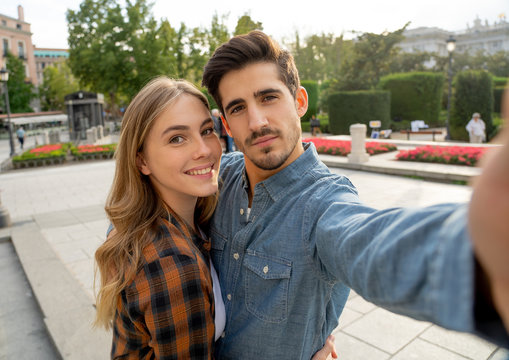 Stylish tourist couple taking pictures selfie on smart phone on romantic trip around Europe