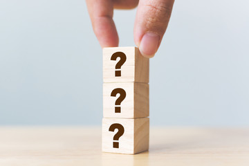 Wooden cube block shape with sign question mark symbol on wood table