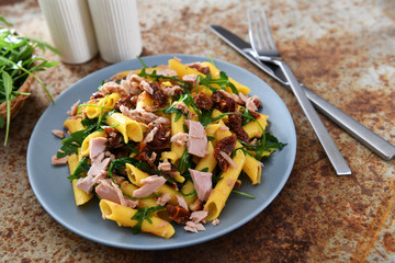 Penne pasta with tuna chunks, rucola and dry tomatoes