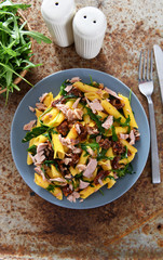 Penne pasta with tuna chunks, rucola and dry tomatoes
