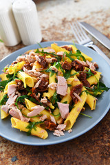 Penne pasta with tuna chunks, rucola and dry tomatoes