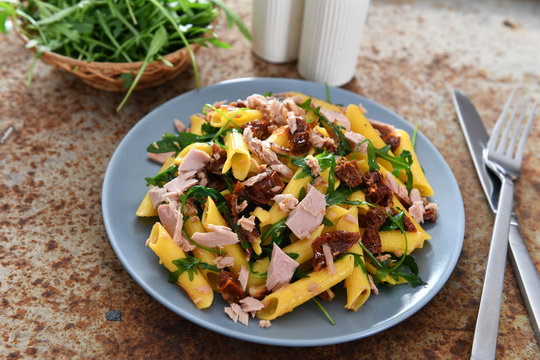 Penne pasta with tuna chunks, rucola and dry tomatoes