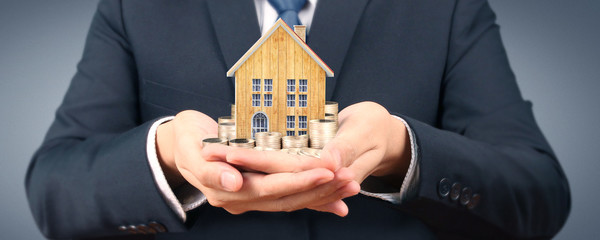 Growing coins house on stack coins in hand. Concept of Investment propert