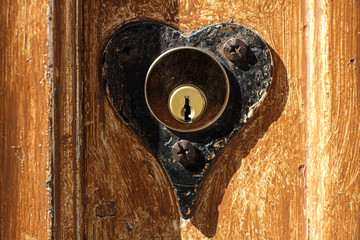 A heart shaped lock for a key on an old wooden door
