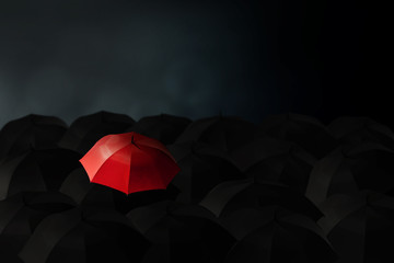 Business Leadership Concept : Red umbrella stand out from group of many black umbrellas.