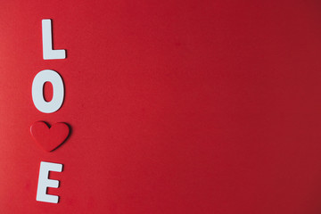 White wooden letters and red wooden hearts on a red background