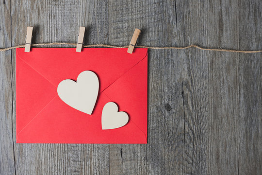 A wooden heart placed on a red envelope And placed on a gray wooden background