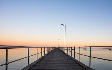 Pier leading out to the distance into the ocean on a clear dawn morning
