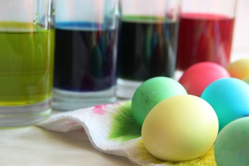 four glasses with blue, yellow, green and red paint, cooking for Easter. painting eggs for the Easter bunny