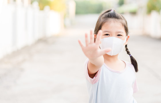 Coronavirus and Air pollution pm2.5 concept.Little chinese girl wearing mask for protect pm2.5 and show stop hands gesture for stop corona virus outbreak.Wuhan coronavirus and epidemic virus symptoms.