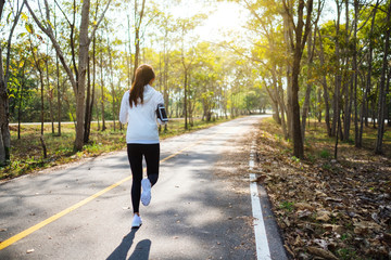 Rear view image of a young asian woman jogging in city park in the morning