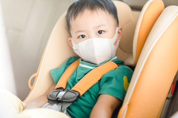 Coronavirus and Air pollution pm2.5 concept.Little chinese boy wearing mask for protect pm2.5.in car seat in the car.Corona virus outbreak.Wuhan coronavirus, epidemic virus symptoms and travel.