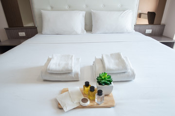 Set of hotel amenities (such as towels, shampoo, soap, gel etc) on the bed. Hotel amenities is something of a premium nature provided in addition to the room when renting a room.