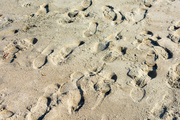 Fototapeta na wymiar Random foot steps from shoes on sandy beach