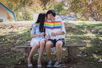 Beautiful lesbian couple holding the rainbow LGBT flag in the hands. LGBT Lesbian Couple Moments Happiness Concept.