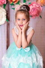 Portrait of surprised girl in turquoise dress with diamond diadem