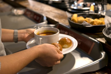 man puts borsch with donuts on his tray in the dining room