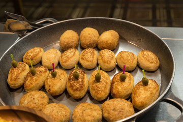 ready-made potato pancakes of different types lie in a large frying pan in the open kitchen of the restaurant