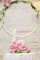 Top of luxurious cake adorned with roses and a one year old white candle