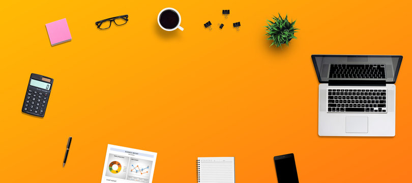 Top view office desk and supplies, with copy space. Creative flat lay photo of workspace desk/Panoramic banner isolated on orange background