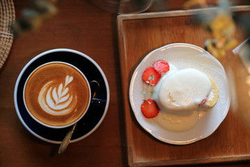 Coffee and strawberry cream cake on wooden table