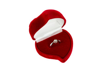 Wedding ring in a red velvet case in the form of a heart on a white isolated background. Platinum with a gem.