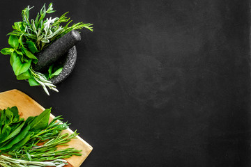 Make seasoning and condiments. Herbs in mortar on black background top-down copy space