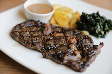 beef steak with potato on wood background