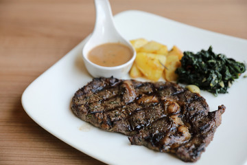beef steak with potato on wood background