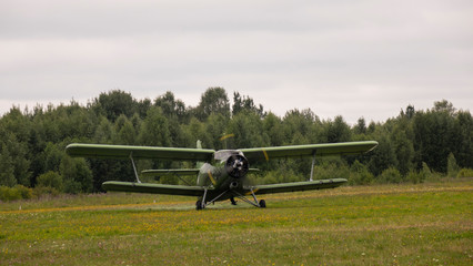 Agricultural airplane stands in a field in the green grass.