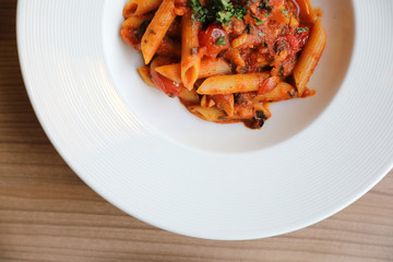 Penne arrabiata pasta tomato sauce with spices italian food on wood background